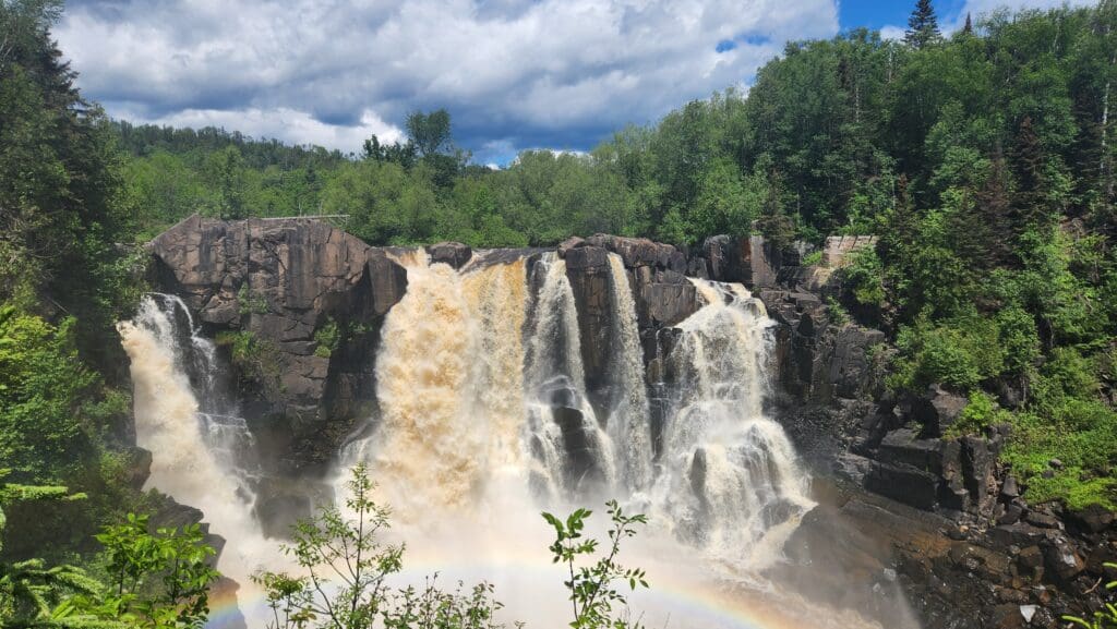 A vibrant rainbow arcs over High Falls at Grand Portage State Park, one of the best state parks in Minnesota.