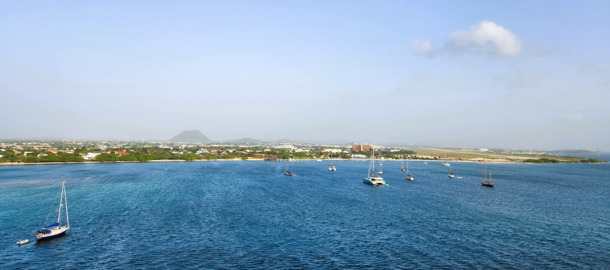 Coastal view of Aruba with clear blue water and anchored boats – popular Caribbean cruise destination