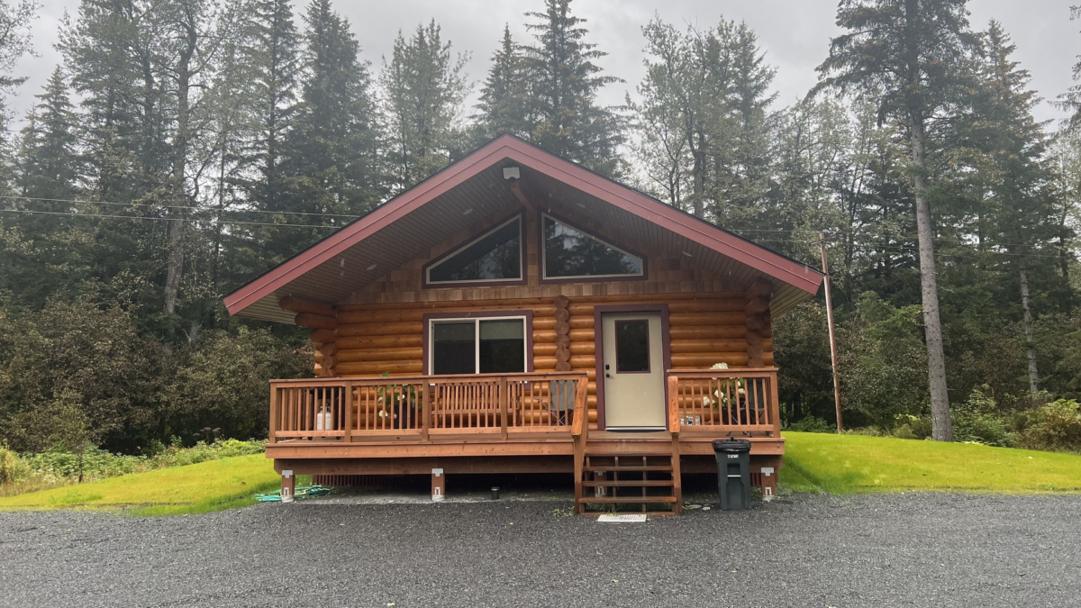 Rustic log cabin at Clear Creek Cabin in Seward, Alaska, surrounded by forest — a cozy rental perfect for families visiting the Kenai Peninsula.