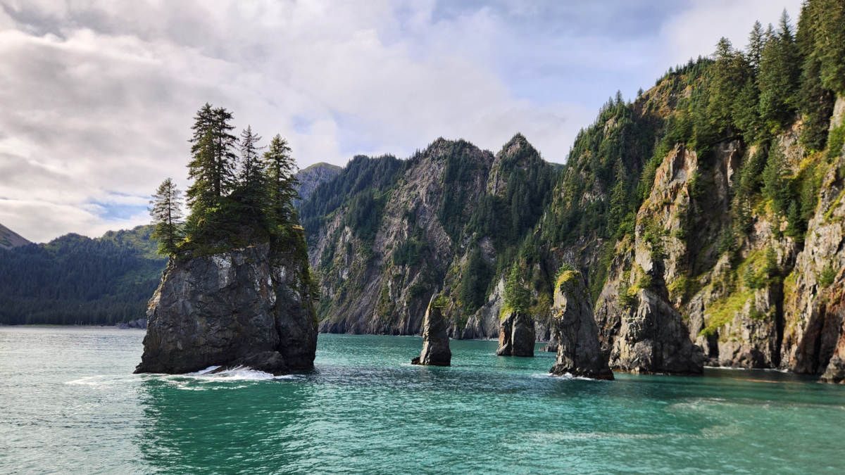 Rock formations rising from turquoise water along the Kenai Fjords National Park coastline during a Major Marine Tours cruise from Seward, Alaska.
