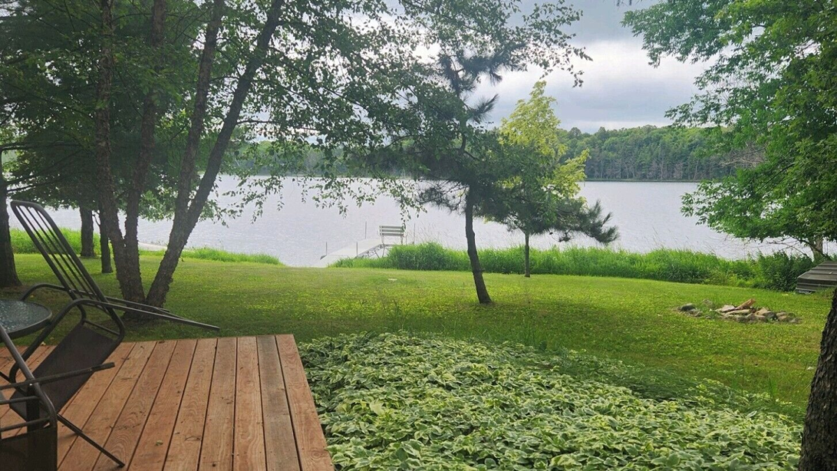 Lakefront view from Bobbers Cabin on Perch Lake near Winter, Wisconsin with dock, trees, and outdoor seating