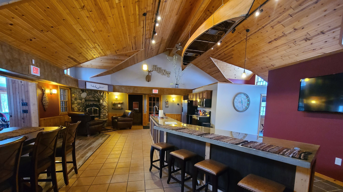 Interior of the Moxi Whitetail cabin near Connors Lake with vaulted wood ceilings, stone fireplace, and spacious kitchen