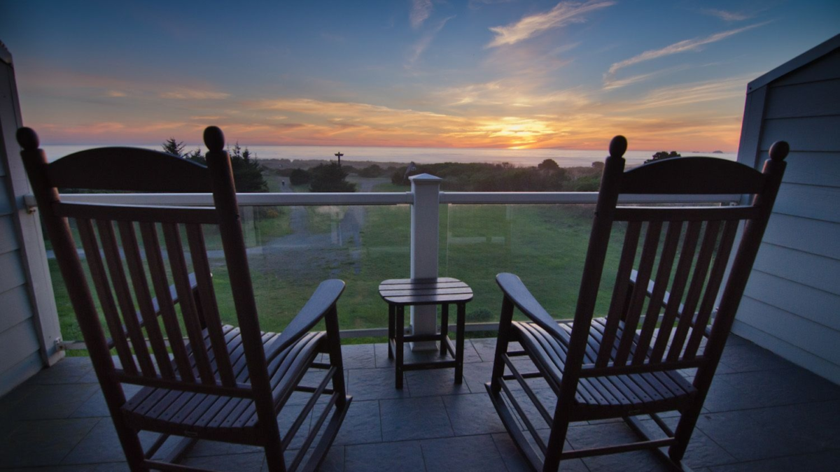 Oceanview balcony at Pacific Reef Hotel in Gold Beach Oregon with rocking chairs overlooking a coastal sunset