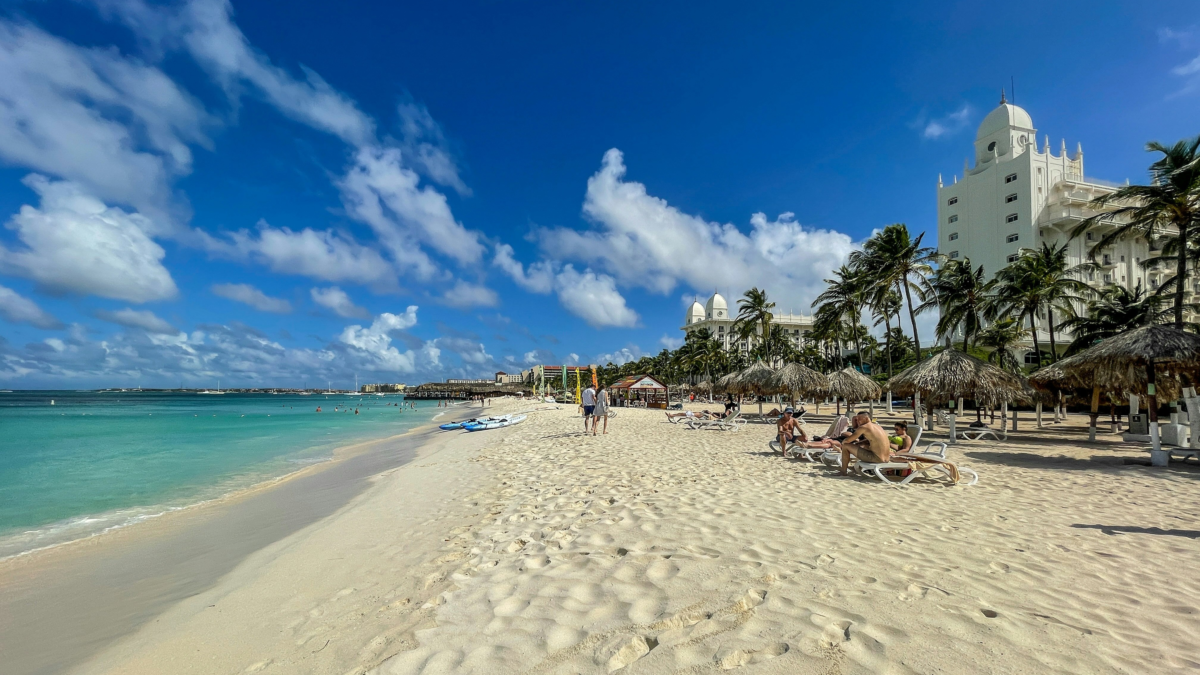 Wide sandy beach in Aruba with turquoise water and beachfront resorts along the shore. snorkeling Aruba beaches