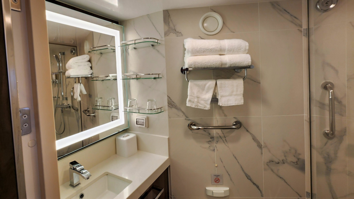 Holland America Rotterdam Verandah Cabin Bathroom Vanity - Dohrn Travels Holland America Rotterdam Verandah cabin bathroom with illuminated mirror and glass shelving