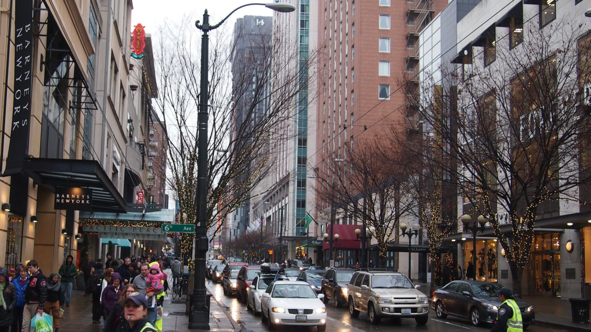 Busy downtown Seattle street lined with shops, restaurants, and holiday lights.