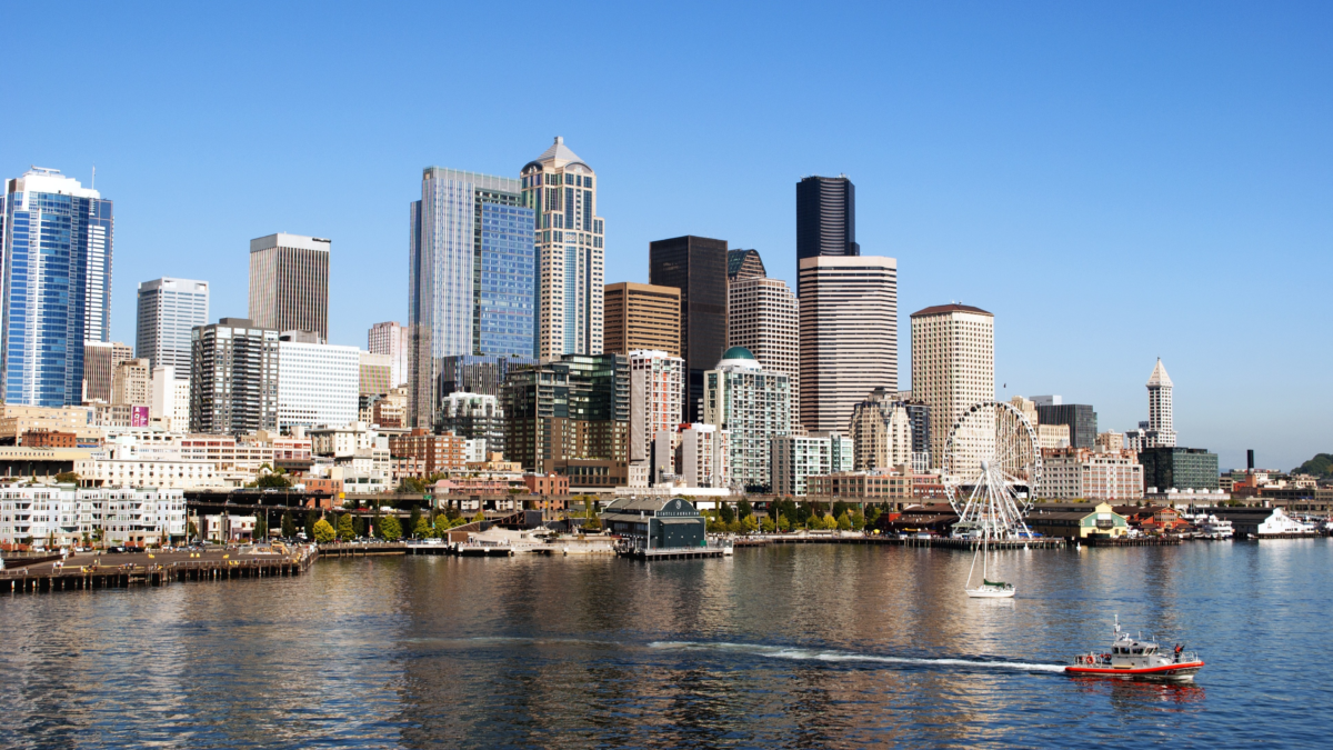 Seattle skyline viewed from Elliott Bay with the Great Wheel and waterfront visible.