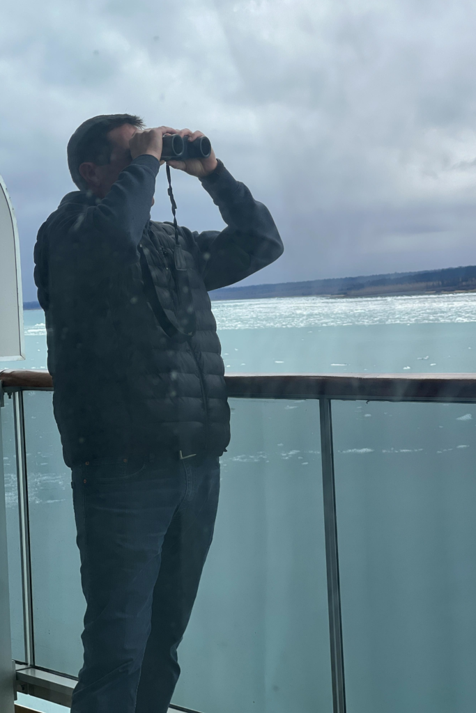 Using Binoculars Near Hubbard Glacier | Dohrn Travels Man using binoculars from a cruise ship balcony while viewing the icy waters near Hubbard Glacier, Alaska.