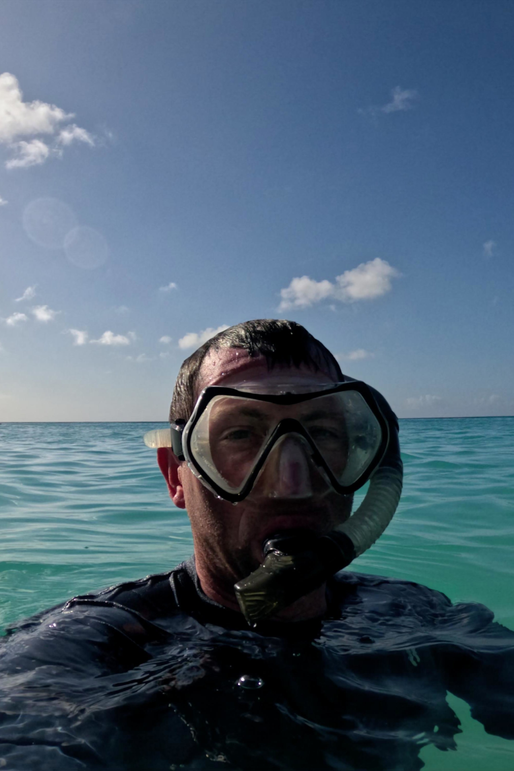 Snorkeler wearing a mask and snorkel in the clear turquoise water off Aruba