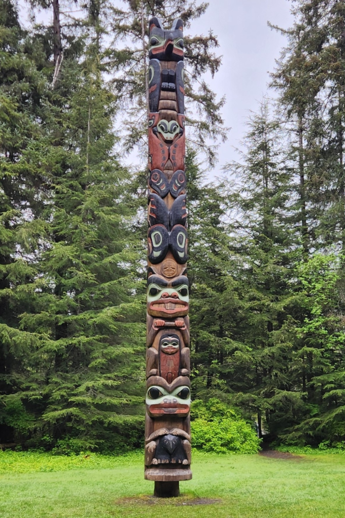 Tlingit totem pole surrounded by forest along the Totem Trail in Sitka Alaska