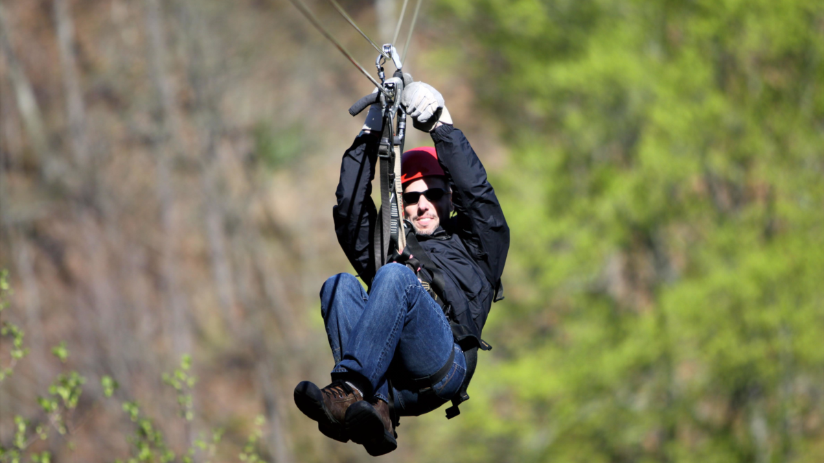Ketchikan Zipline Shore Excursion | Dohrn Travels Cruise passenger ziplining through Alaska rainforest near Ketchikan.