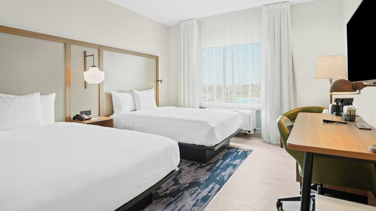 Fairfield by Marriott Fort Lauderdale Airport guest room with two beds, desk, television, and window