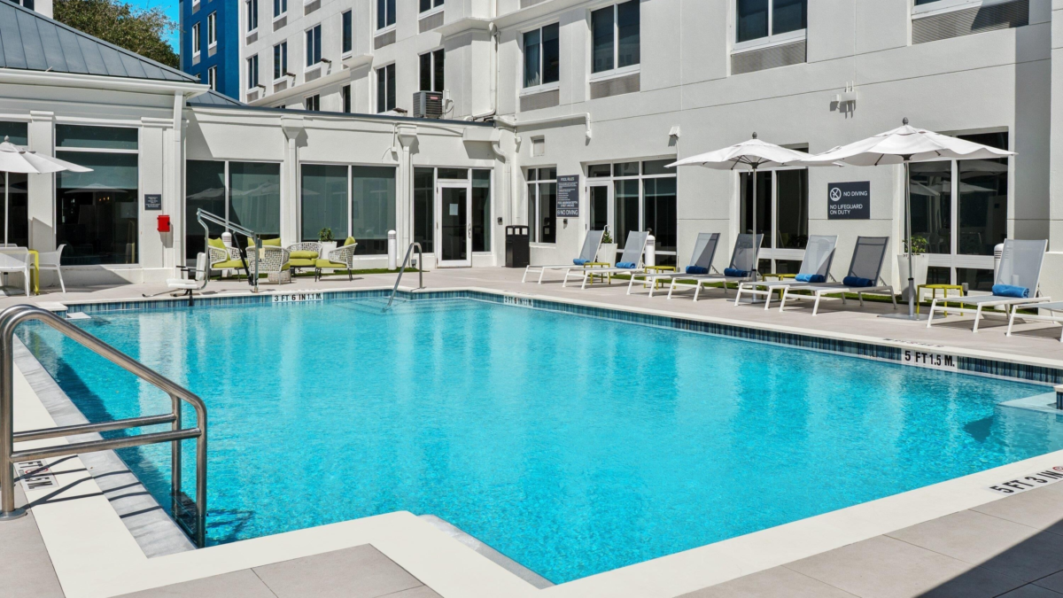 Outdoor pool at Hilton Garden Inn Fort Lauderdale Airport with lounge chairs and umbrellas