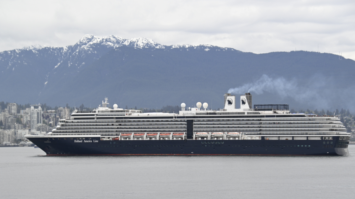 Holland America Zuiderdam cruise ship sailing with snow-covered mountains in the background