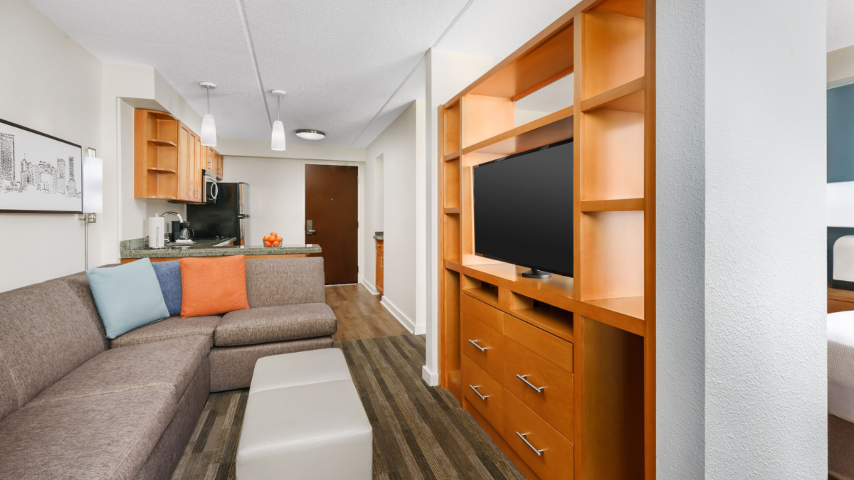 Hyatt House Fort Lauderdale Airport suite with living area, kitchen, sofa, TV, and separate sleeping space