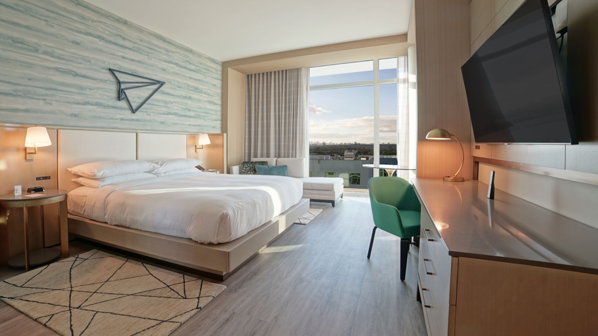 Modern guest room at Marriott Fort Lauderdale Airport with king bed, desk, large TV, and floor-to-ceiling windows